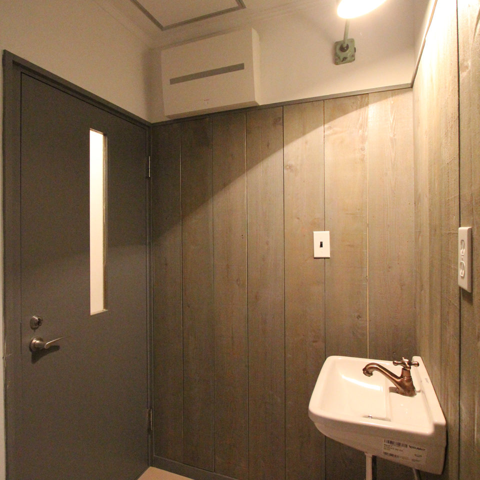 木板張りの壁と手洗い器とドア