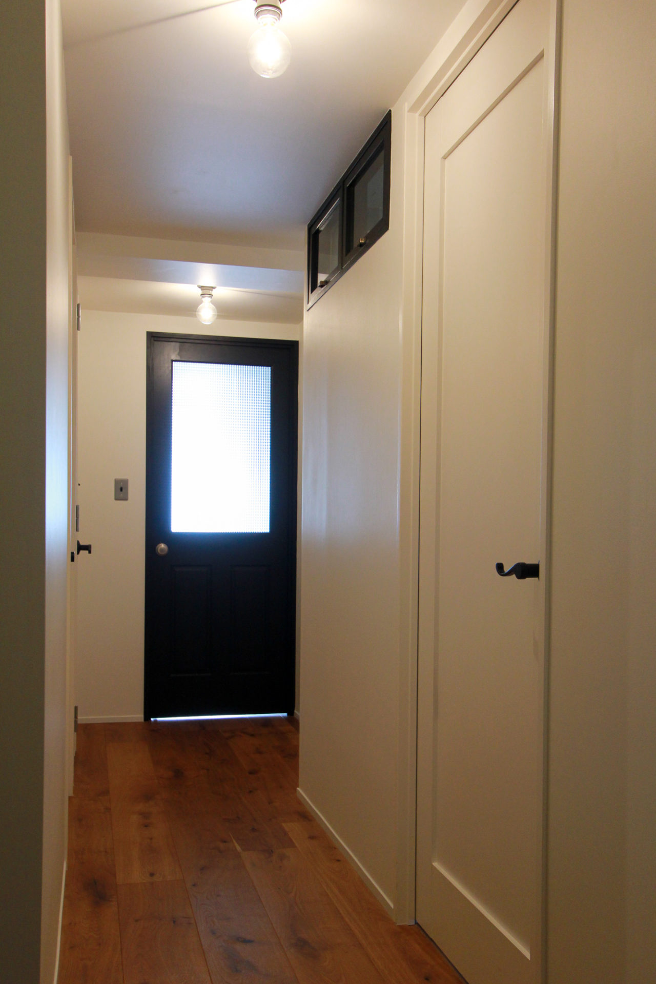 オーク材フローリングの廊下と黒いリビングドア
