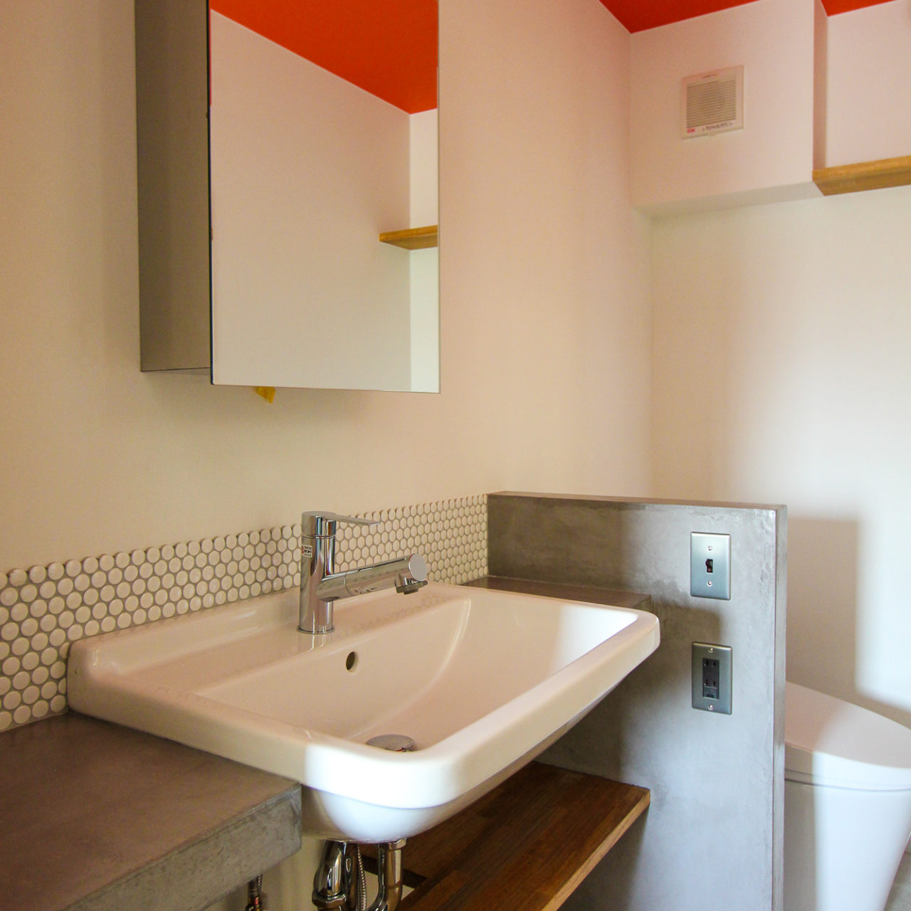オレンジ色の天井とコンクリート天板の洗面室