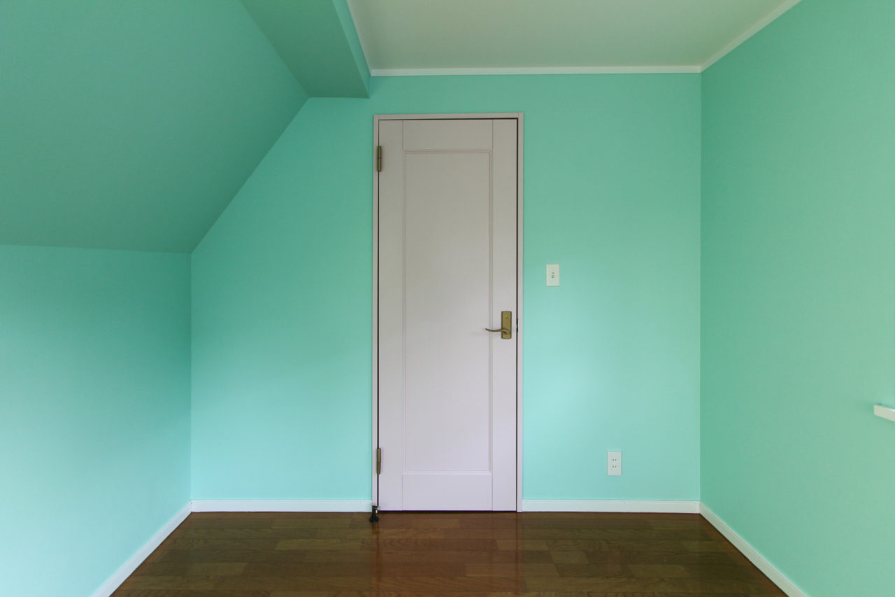 淡いグリーンの壁とピンク色のドア
