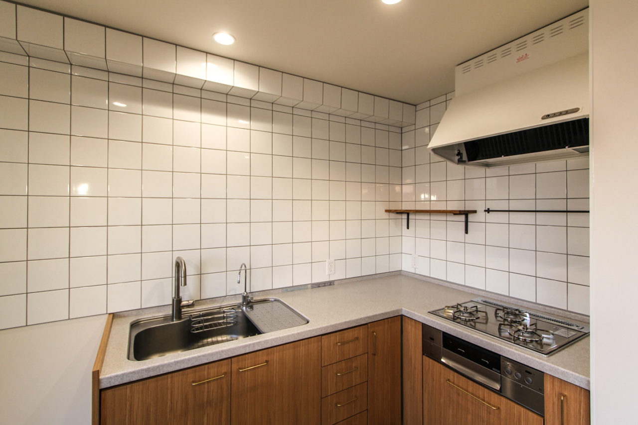 白いタイル貼りと扉や設備を変えたキッチン
