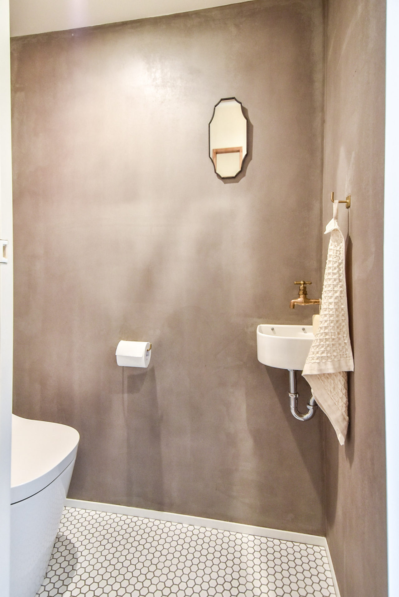 モルタルの壁とモザイクタイルの床のトイレ