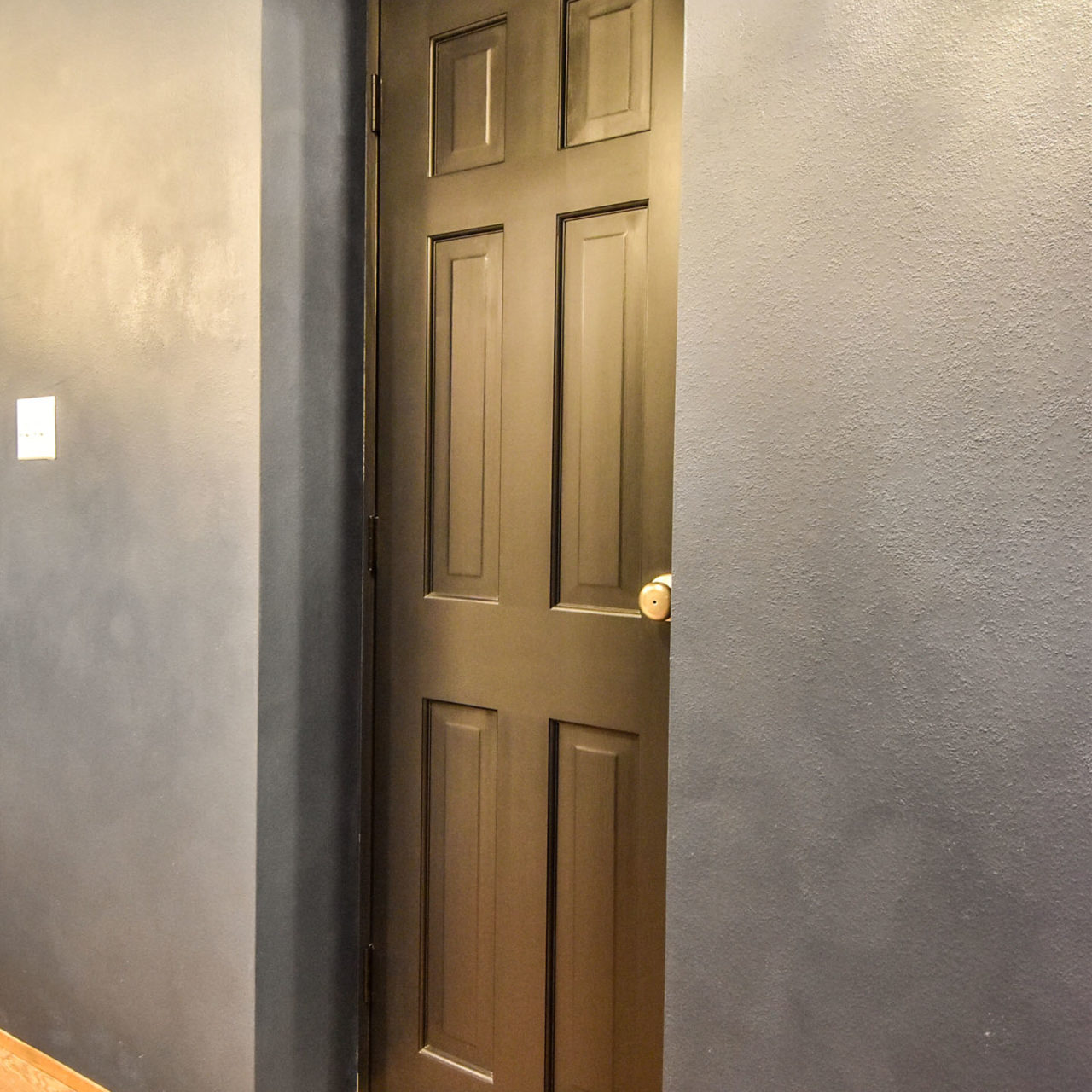 ネイビーの壁と黒の木製ドア