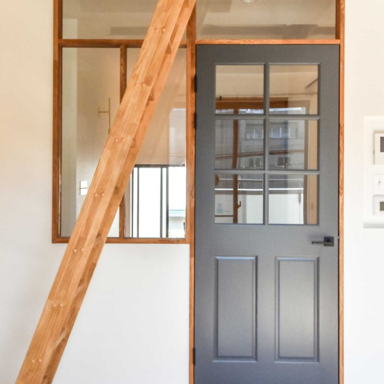 ロフトへの木製はしごと木製ドアと室内窓