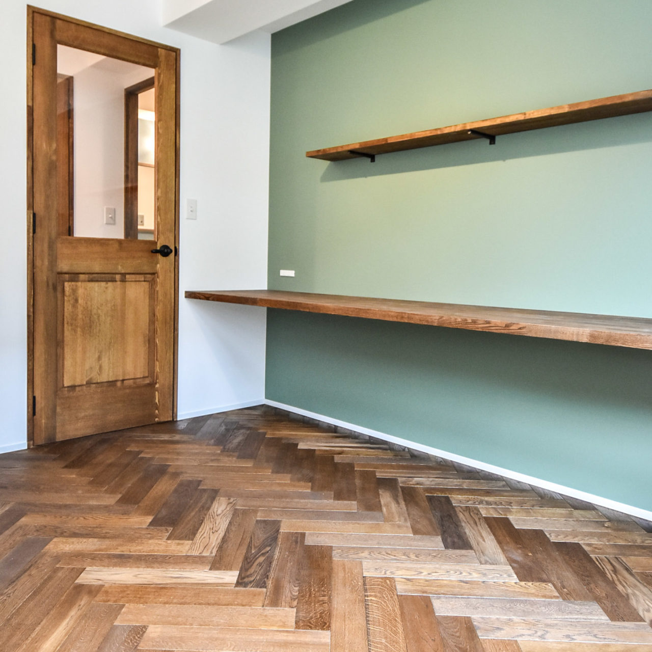 ヘリンボーンの床とカウンターデスクと木製ガラスドア