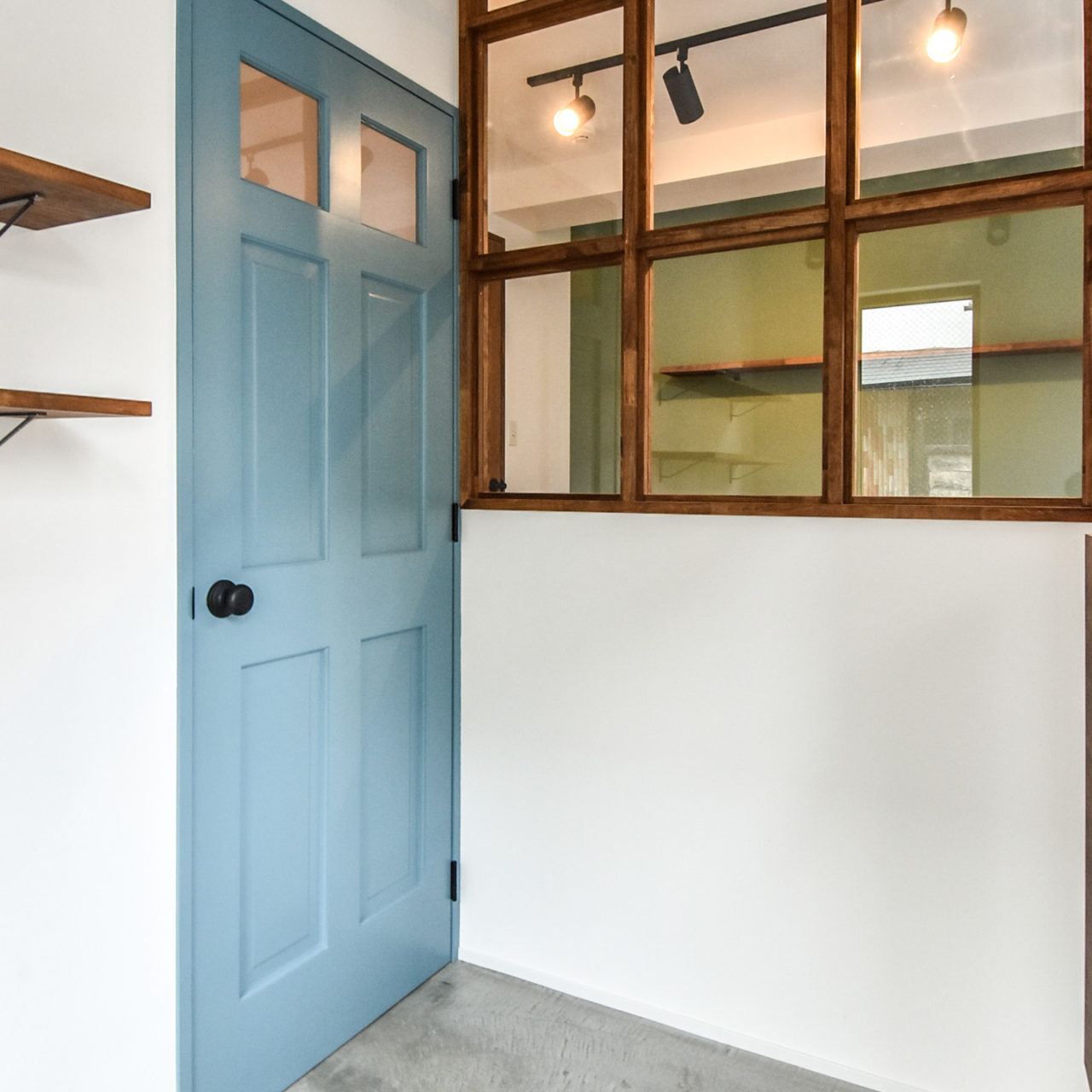 玄関の土間と水色のドアと木製の室内窓