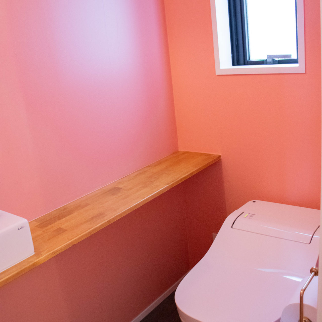 ピンクの壁と木製カウンターのあるトイレ