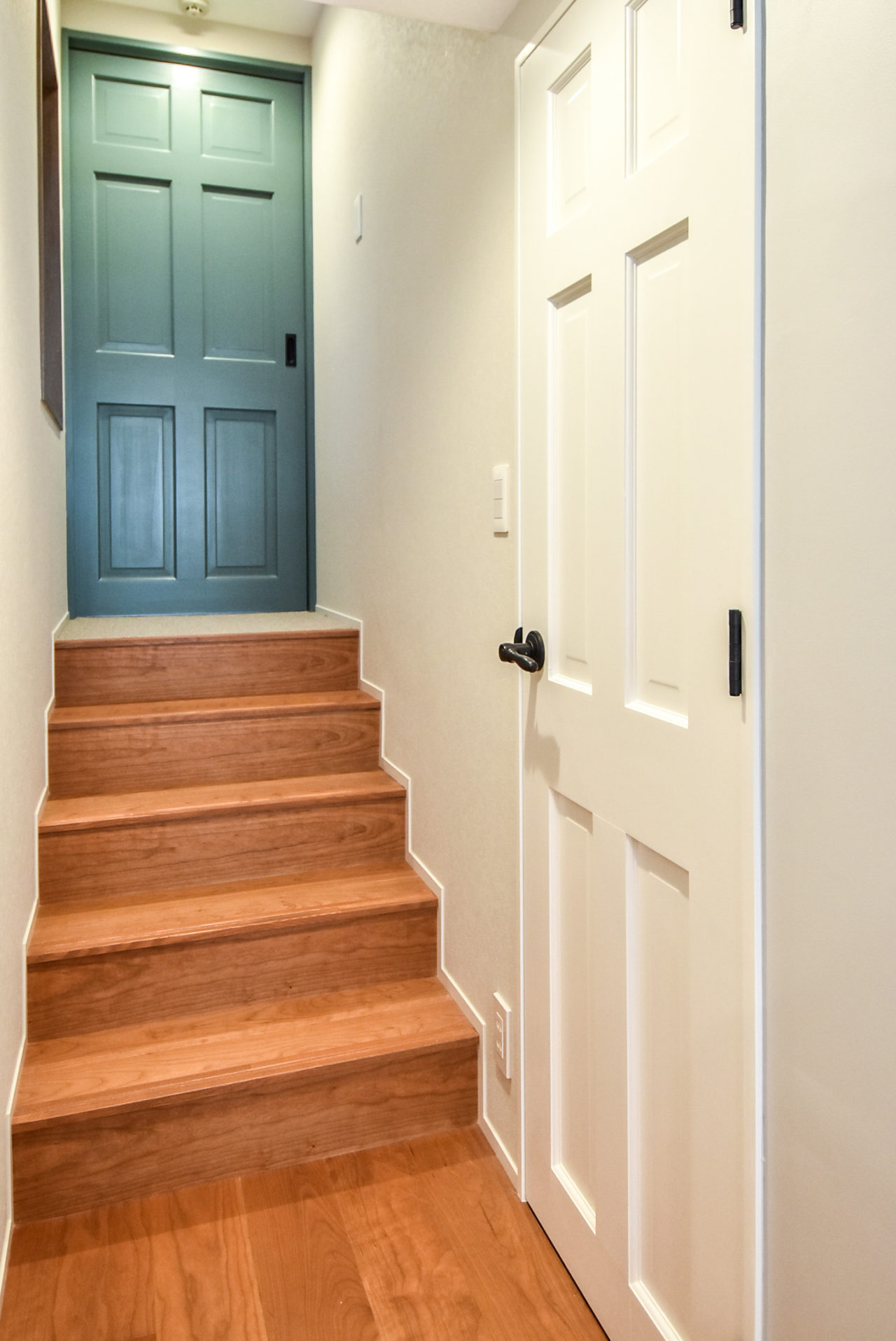 ブルーグリーンのドアと階段と白いドア