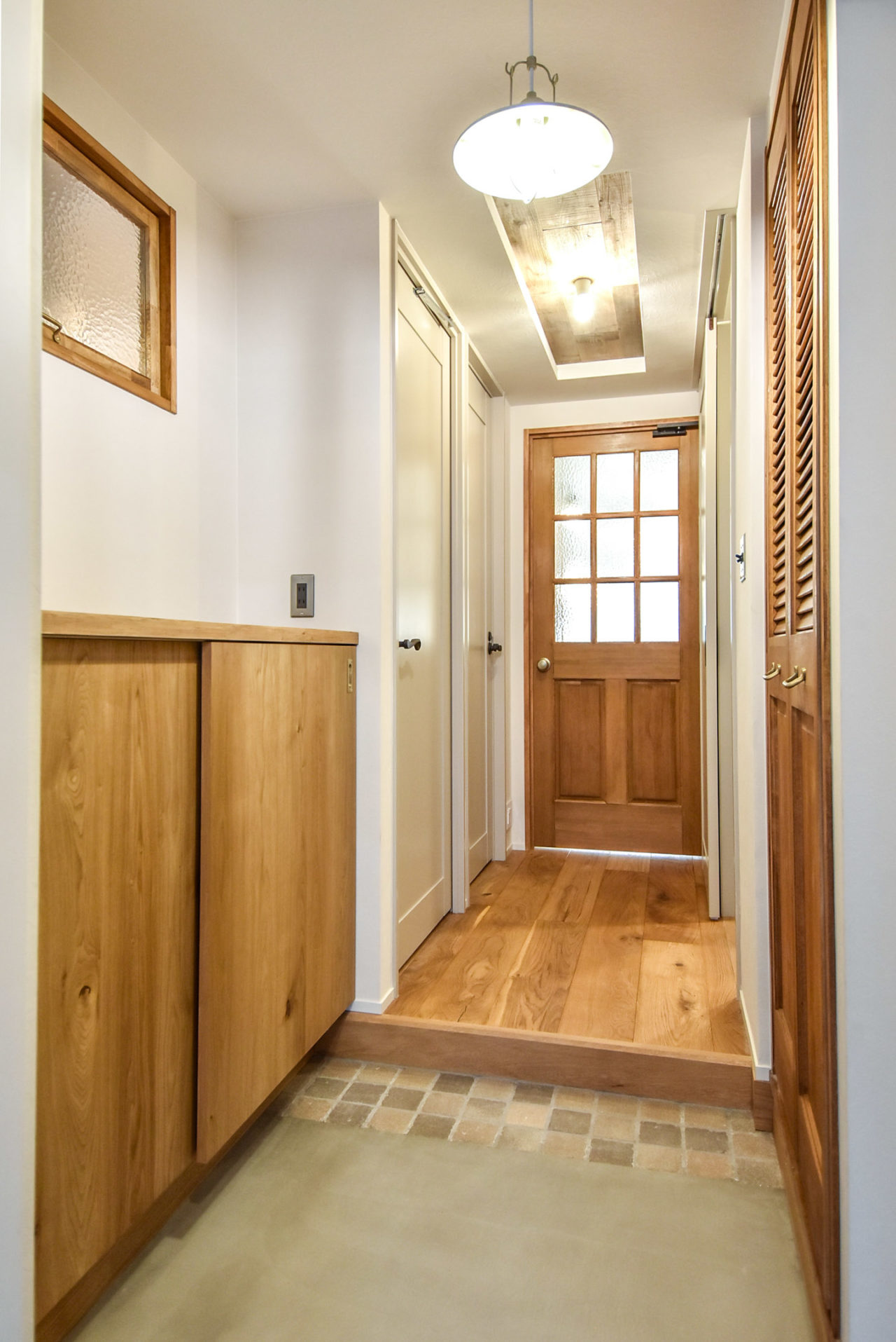 木製の玄関収納と室内窓のある玄関
