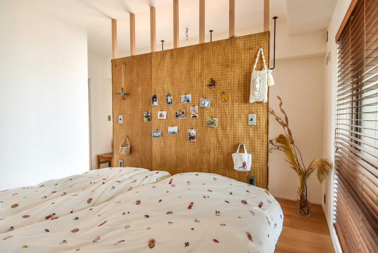 有孔ボードのパーテーションに写真が飾られたベッドルーム