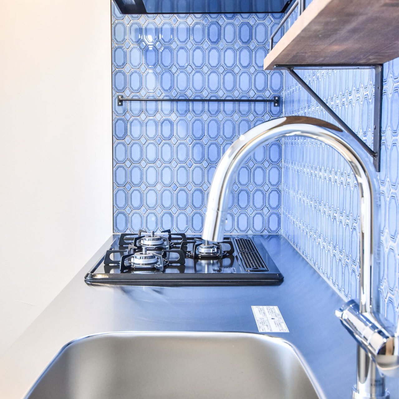鮮やかなブルーのタイルの壁とグースネックのキッチン水栓
