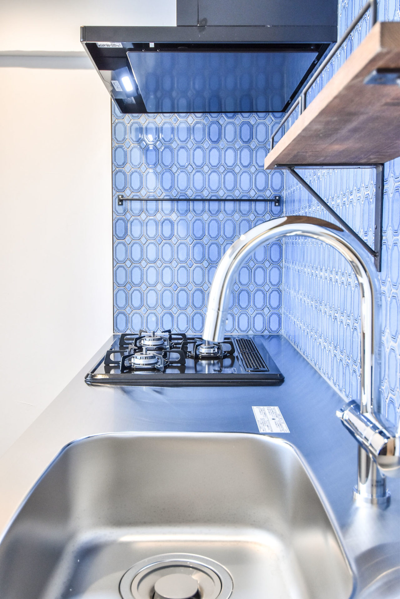 鮮やかなブルーのタイルの壁とグースネックのキッチン水栓
