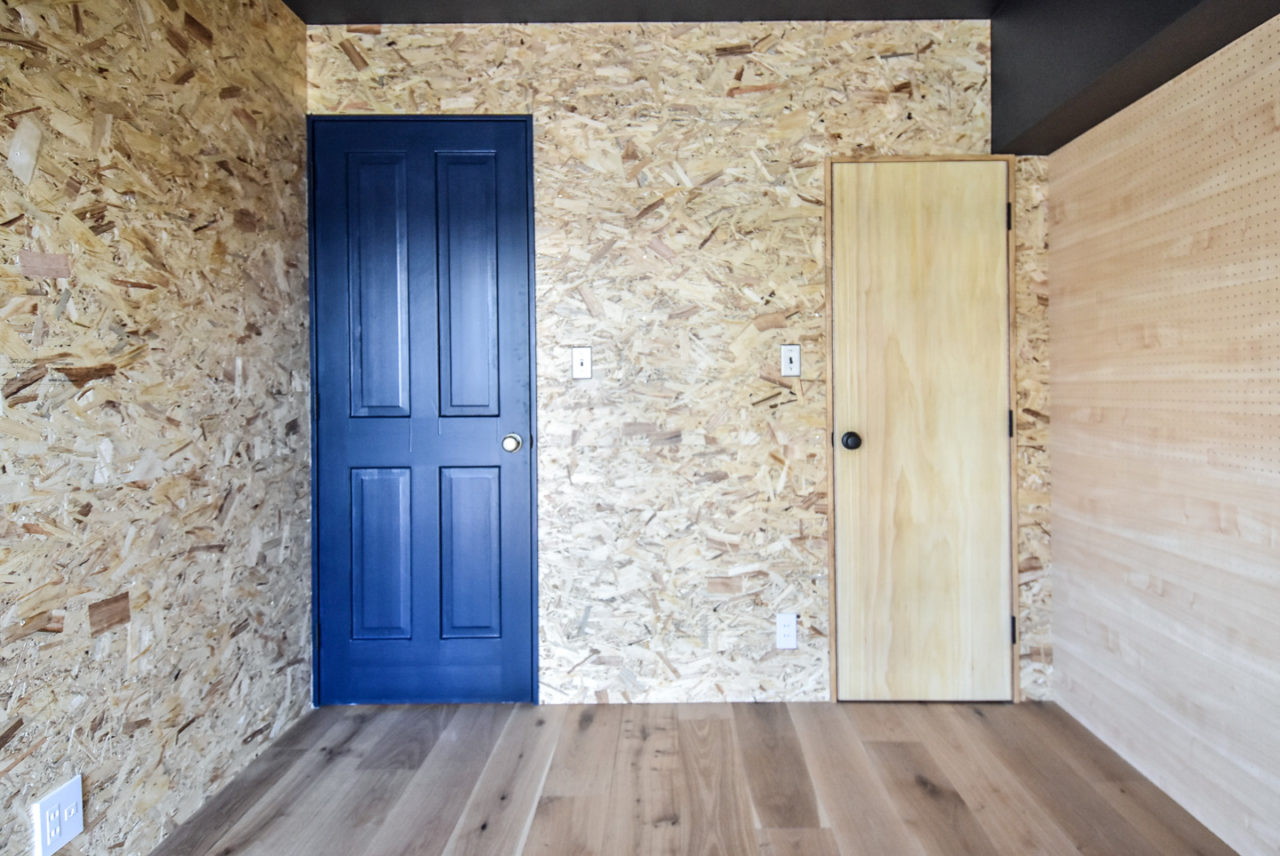 OSBボードの壁と黒の木製ドア
