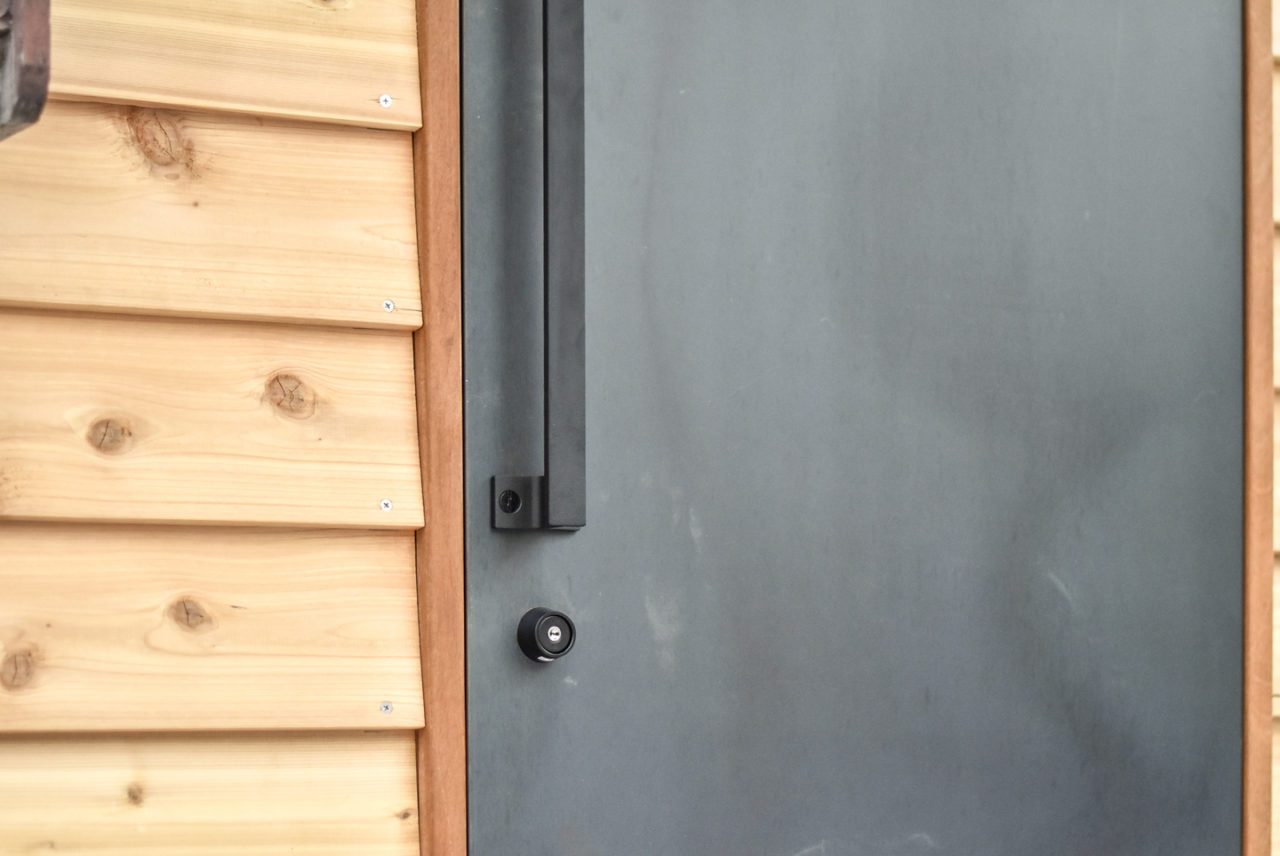 スチールの庇と木板貼りの壁と黒皮鉄の玄関ドア