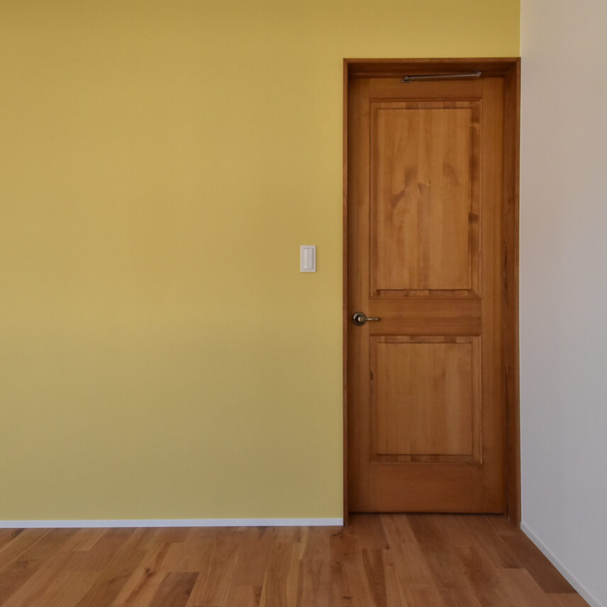 黄色い壁と木製ドアの洋室
