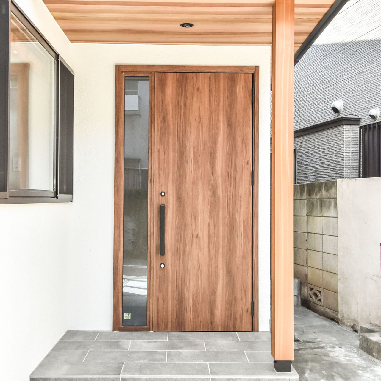 タイル貼りの玄関ポーチと木調の玄関ドア