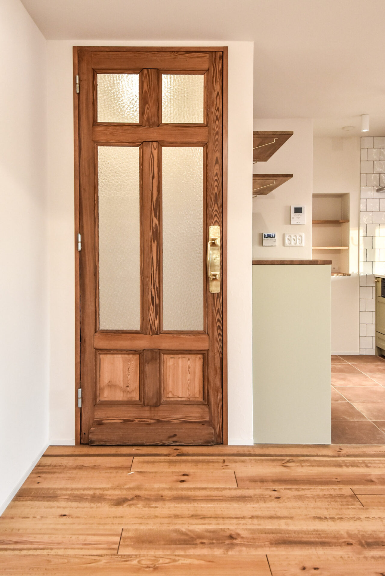木製のクラシックなドア、ガラスの窓と白い壁、背景にオープンキッチン