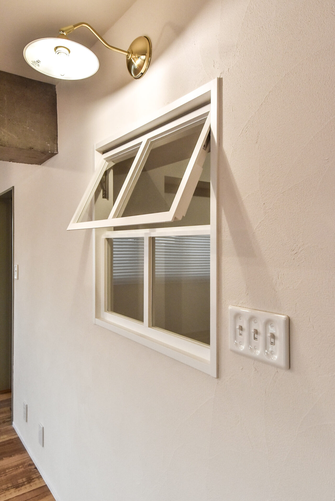 白い壁と小さな窓、露出したコンクリート梁のあるリビングルーム