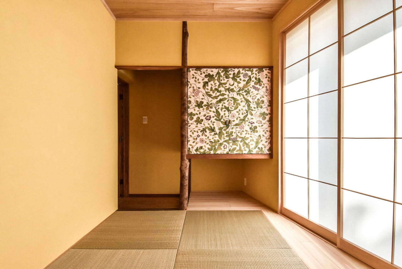 黄色い壁と縁無し畳、植物柄の収納扉のある和室