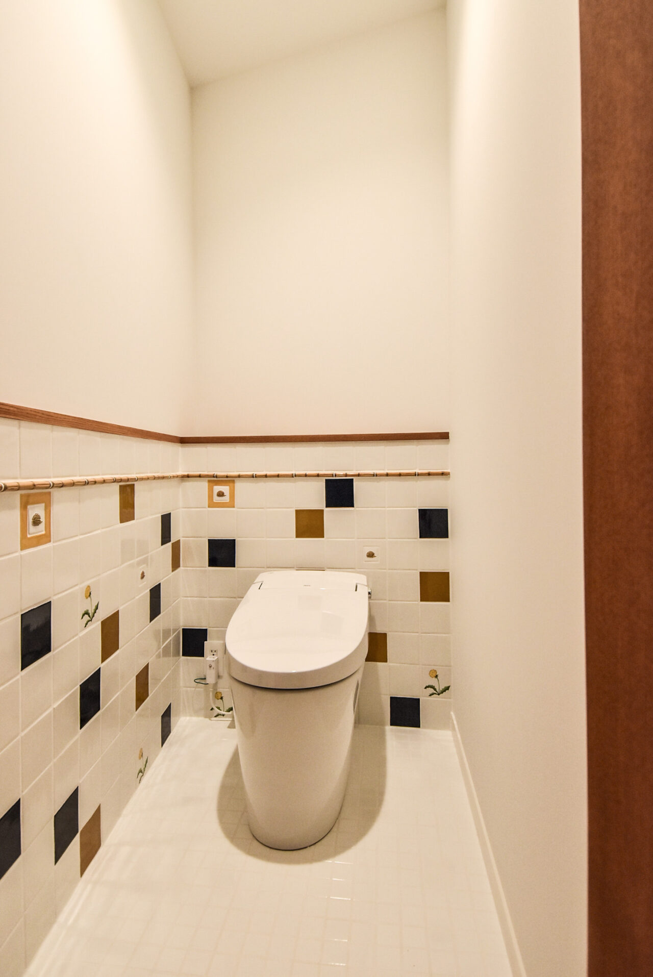 床と腰壁のタイルが特徴的なトイレ