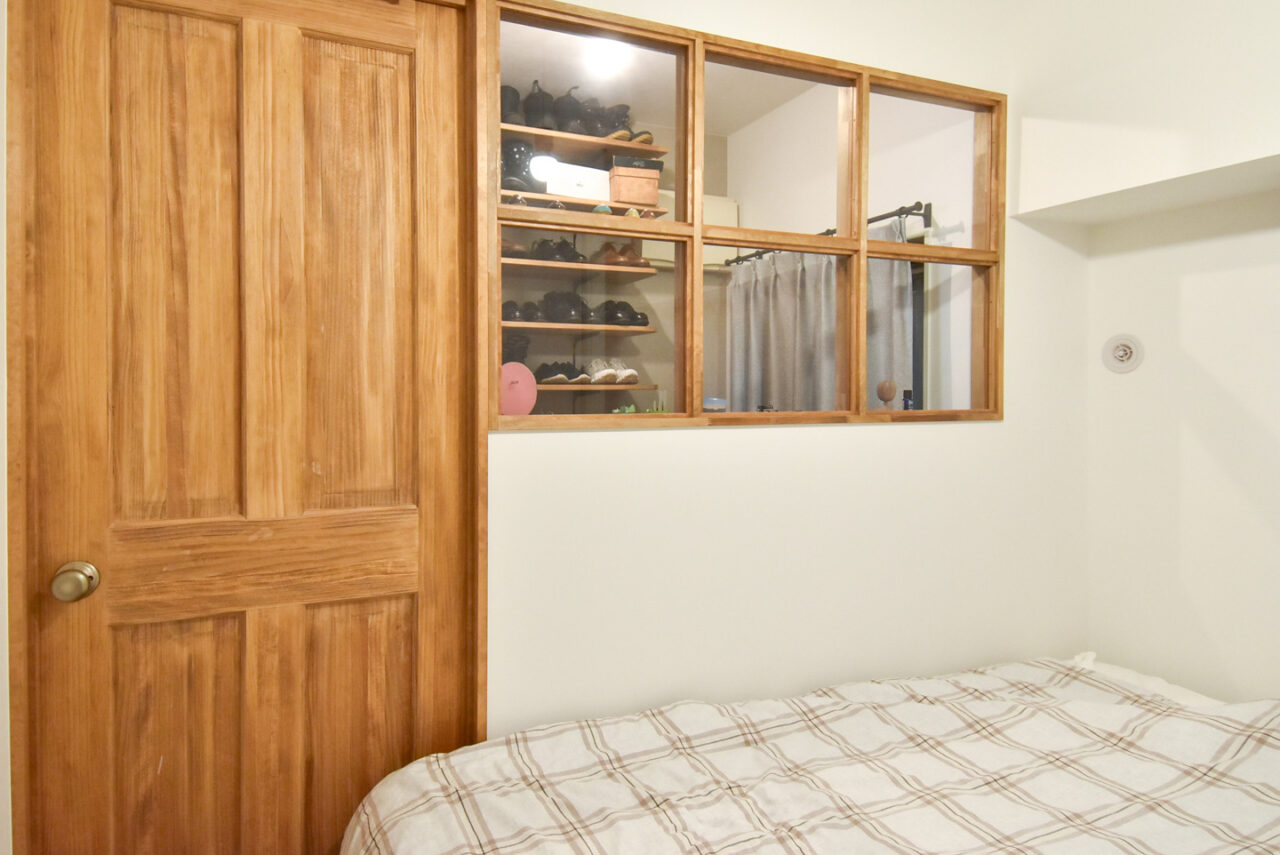 玄関と寝室の間の壁の室内窓と木製のパネルドア