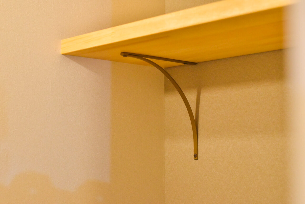 シンプルな木製の棚のクローズアップ。メタルのブラケットで壁に固定されています。
